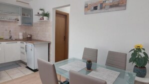 Une cuisine moderne avec des meubles blancs, un petit réfrigérateur et un plan de travail sur lequel se trouve un grille-pain.