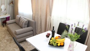 Ein modernes Wohnzimmer mit einer Couch, einem Esstisch mit Früchten und einer Flasche sowie Blick ins Freie.