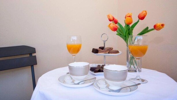 Ein Frühstücksarrangement mit Orangensaft, einer kleinen Dessertplatte und einem Strauß Tulpen auf einem Tisch.