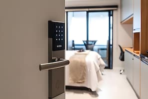 Ein modernes Hotelzimmer mit digitalem Schloss, einem Bett, einem Essbereich und Blick ins Freie.