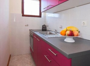 Eine Küche mit Spüle, Obstschale und Fenster.