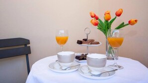 A breakfast setup with orange juice, a small dessert plate, and a vase of tulips on a table. - Guest House Stay & Smile Dolac Primošten - Studio with Sea View and Balcony (Primosten)