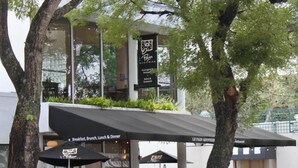 Un café en plein air avec une enseigne indiquant qu’il sert le petit-déjeuner, le brunch, le déjeuner et le dîner.