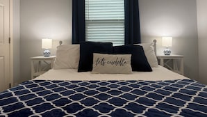 A bedroom with a bed, two bedside tables with lamps, a window with curtains, and a pillow with text. - No Cleaning Fee  Quiet Stay Near Base & Memphis  Fast WiFi (Millington)
