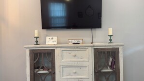 A white, distressed wooden console table with a flat-screen TV mounted above it. - No Cleaning Fee  Quiet Stay Near Base & Memphis  Fast WiFi (Millington)