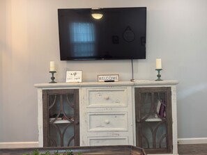 A white, distressed wooden console table with a flat-screen TV mounted above it. - No Cleaning Fee  Quiet Stay Near Base & Memphis  Fast WiFi (Millington)