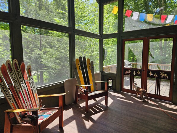 Ein Zimmer mit großen Fenstern, Holzmöbeln und Ski, die an der Wand lehnen.