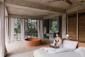 Ein modernes Schlafzimmer mit einem großen Bett, einer Badewanne und Blick ins Grüne.