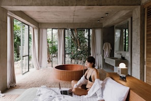 Ein Zimmer mit einer großen Badewanne, einem Bett, einem Laptop und einer Kamera auf einem Holztisch.