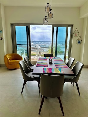 A dining area with a large table, chairs, and a view of the ocean. - Ocean View Apartment : Playa Escondida, Panama (María Chiquita)