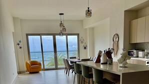 Una cocina moderna con una isla central, taburetes de bar y un comedor con vista al océano.