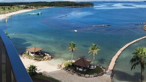Vista costera con aguas transparentes, una playa y una pequeña construcción con techo.