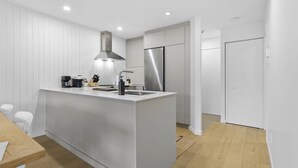 Una cocina moderna con una isla central, electrodomésticos de acero inoxidable y armarios blancos.