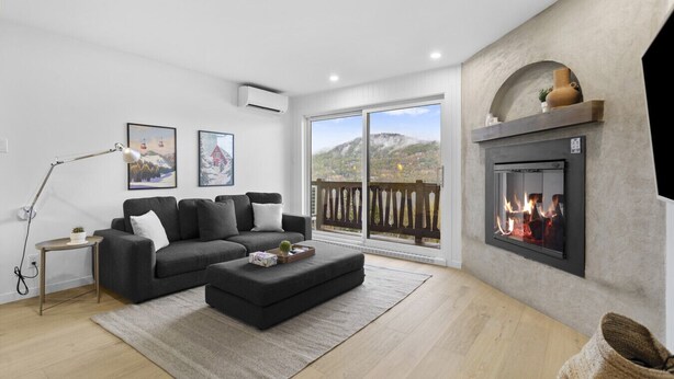 Una sala de estar moderna con chimenea, un sofá, una mesita de centro y un balcón con vistas.