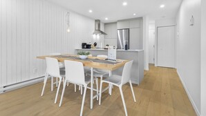 Una cocina moderna con muebles blancos, una mesa de comedor de madera y sillas blancas.