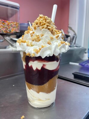 Ein mehrschichtiges Dessert in einem Glas, mit Schlagsahne und Granola belegt.