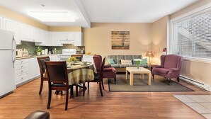 A modern kitchen with white cabinets, a dining table with chairs, a sofa, and a coffee table.