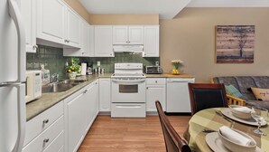 A modern kitchen with white cabinets, a built-in oven, and a dining area with a table set for two.
