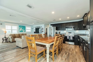 A modern kitchen with dark cabinets, stainless steel appliances, and a wooden dining table with chairs.