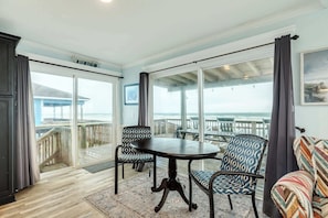 A balcony with a table and chairs, a view of the ocean, and a wooden deck.