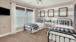 A bedroom with two beds, a desk, a TV, and a ceiling light fixture. - House of Whimsy (Tybee Island)