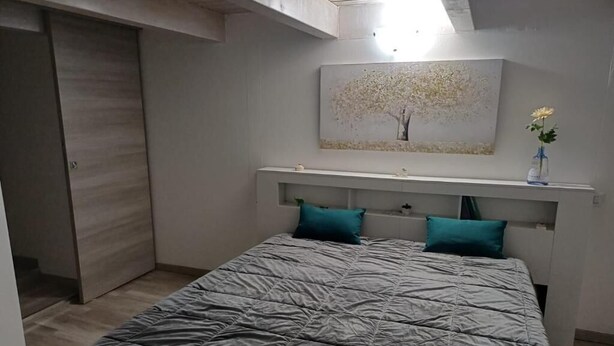 A bedroom with a bed, a headboard, a painting, and a vase with a flower. - B & B Sotto il lago (Nemoli)