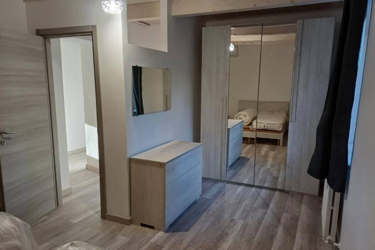 Ein Zimmer mit Holzboden, einem Spiegel, einem Schminktisch und einer Schiebetür zu einem weiteren Raum.