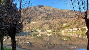 A serene lakeside view with a bench, trees, and buildings in the background. - B & B Sotto il lago (Nemoli)