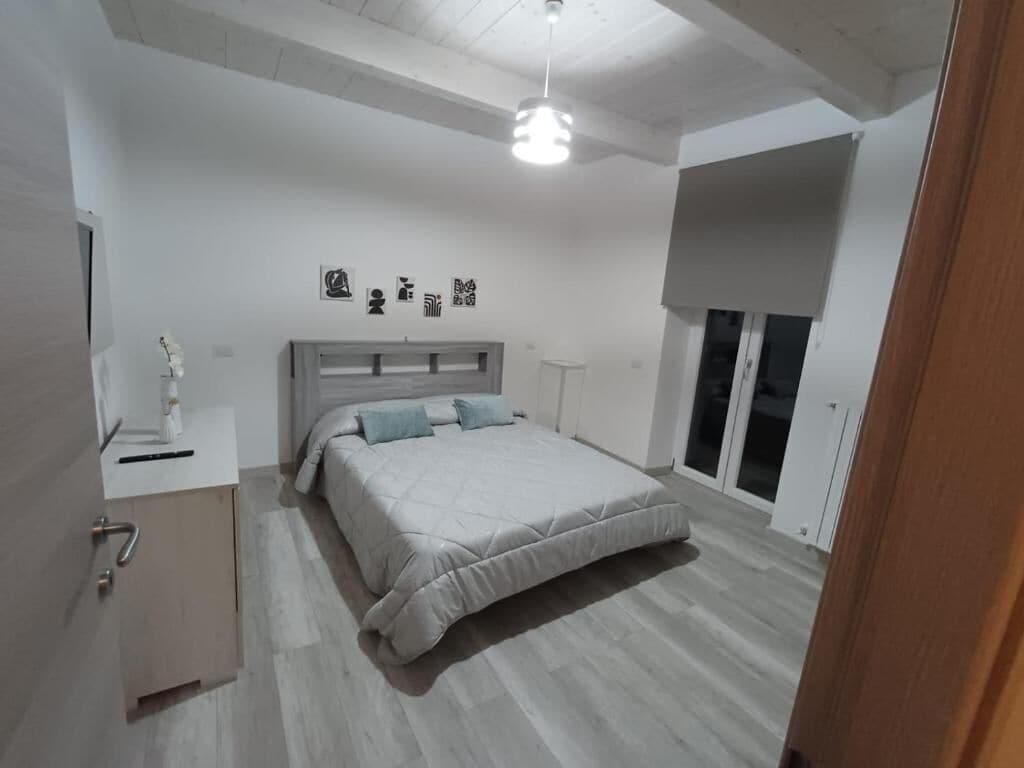 Un dormitorio con cama, mesita de noche y ventana con vistas.
