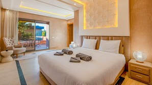 Een moderne hotelkamer met een groot bed, een zithoek met een stoel en een tafel, en door een glazen deur zicht op een terras.