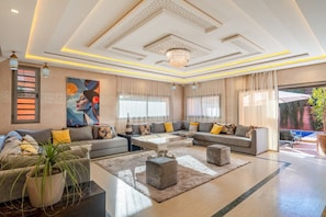 A spacious living room with a large sofa set, a coffee table, and a chandelier. - Luxury 4BR Villa | B&B Available | Pool&Atlas View (Douar Moulay Abbas)
