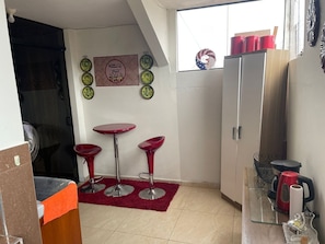 A compact kitchen with a dining area, including a small table and two bar stools. - Apartment for two people in Lima, Peru. (Breña)