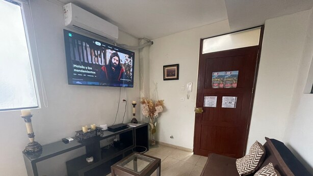 Ein Wohnzimmer mit Fernseher, einer Couch, einem Couchtisch und einer Tür mit Preisschild.