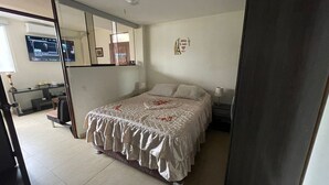 Ein Schlafzimmer mit Bett, Schreibtisch, Stuhl, Spiegel und Deckenventilator.