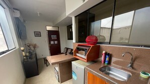 Eine kompakte Küche mit integriertem Mikrowellenherd, Spüle und kleinem Kühlschrank.