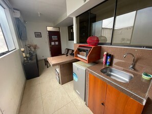 A compact kitchen with a built-in microwave, a sink, and a small refrigerator. - Apartment for two people in Lima, Peru. (Breña)