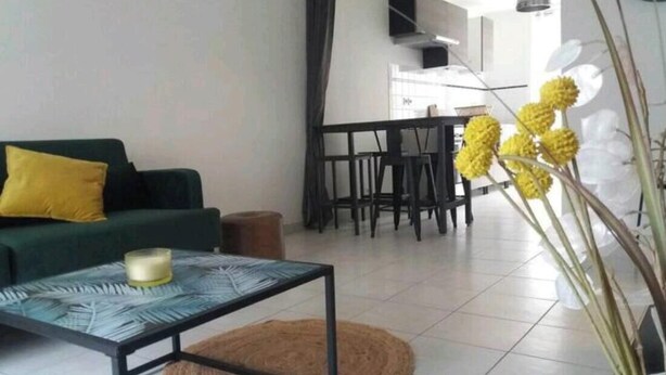A living room with a sofa, coffee table, and a dining area with chairs.