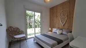 Une chambre à coucher comprenant un lit, une chaise, un bureau et une décoration murale en macramé.