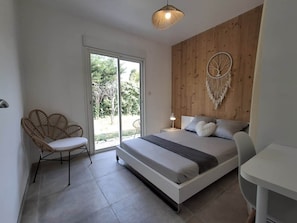 A bedroom with a bed, a chair, a desk, and a macrame wall hanging. - Bioclimatic villa for 8, swimming pool, quiet location (Grasse)