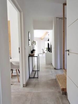 A modern interior with a hallway leading to a dining area, a kitchen, and a living space. - Bioclimatic villa for 8, swimming pool, quiet location (Grasse)