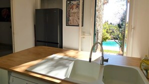 A kitchen with a wooden countertop, a sink, a black refrigerator, and a framed picture on the wall. - Mas Saint Jeaume villa et piscine 10 personnes (Châteauneuf)