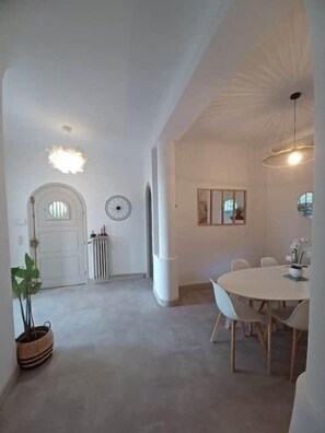 Ein geräumiges Zimmer mit großem Fenster, einem runden Tisch und einem Stuhl.