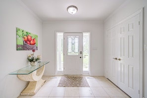 A hallway with a glass console table, a door with a stained glass window, and a white door on the right. - cozy and peaceful quite house  in markham (Markham)