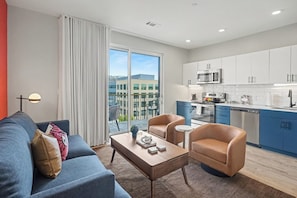 A modern apartment with a living room, kitchen, and balcony. - Music Row Hotel (Nashville)