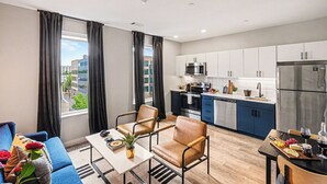 A modern apartment with a kitchen, dining area, and a view of the city. - Music Row Hotel (Nashville)