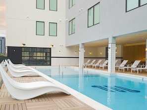 A modern hotel pool area with a long slide, lounge chairs, and a clear view of the building's exterior. - Motif (Nashville)