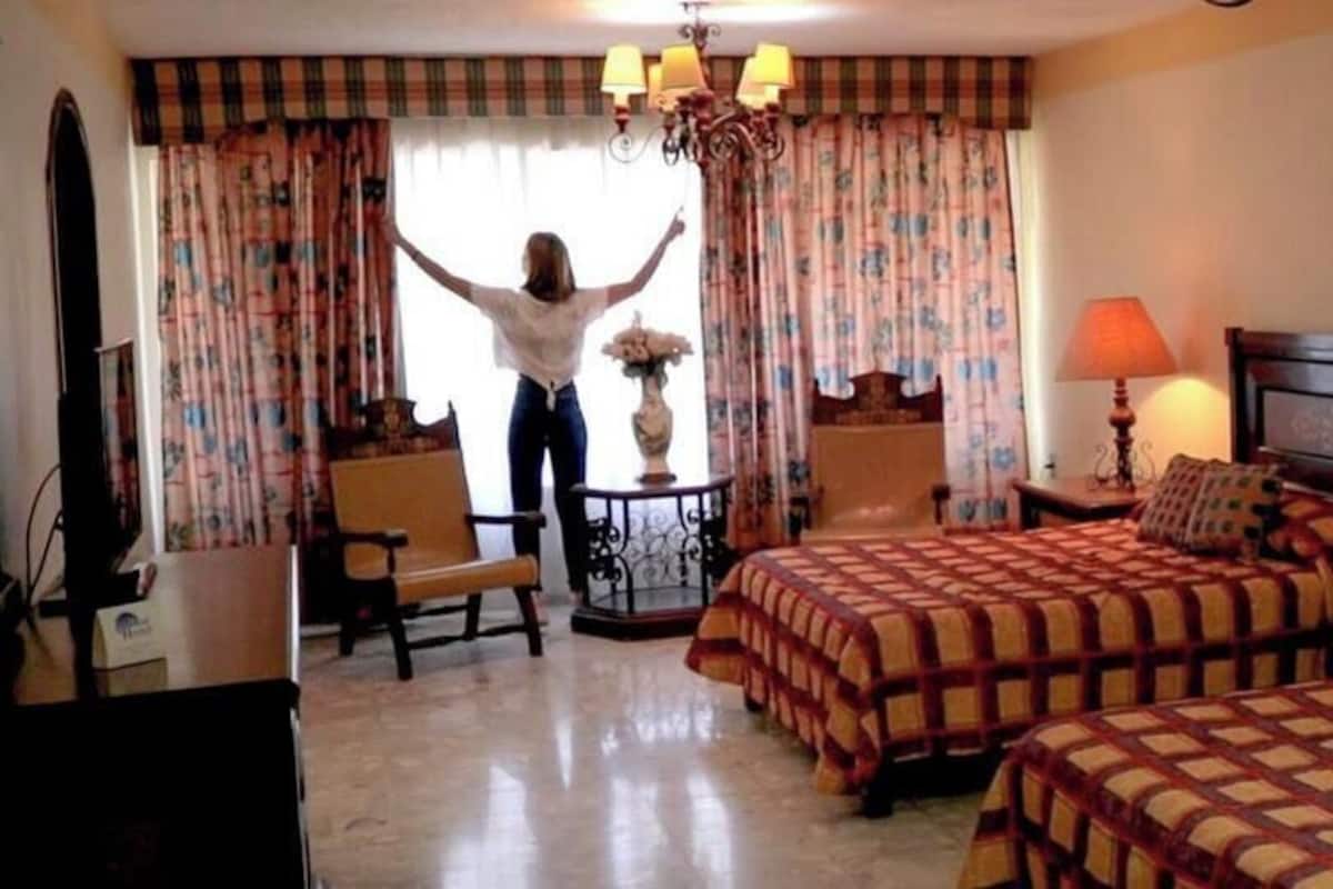 Una habitación de hotel con dos camas, televisión, escritorio con lámpara y una silla.