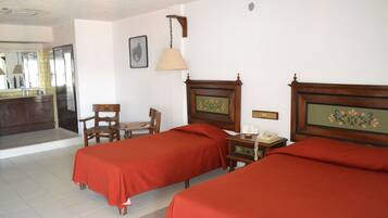 Une chambre d’hôtel avec deux lits, une table de chevet en bois, une chaise, un bureau, une lampe et un miroir.