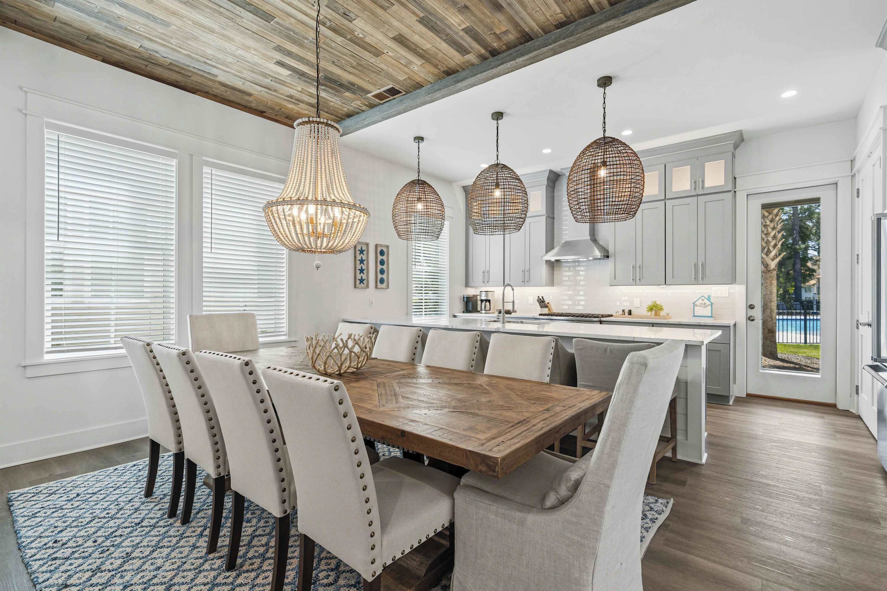 Une cuisine moderne dotée d’un îlot central en bois, de luminaires suspendus et d’un coin repas avec des chaises rembourrées.