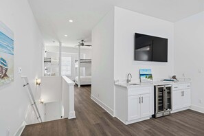 A modern kitchen with white cabinetry, a built-in refrigerator, and a flat-screen TV mounted on the wall. - Community pool, Hot Tub + Tops'l Beach Access (Miramar Beach)
